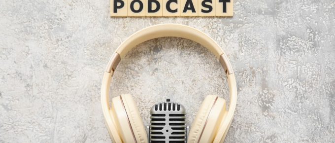 Cuvântul Podcast înconjurat de căști și un microfon pe un fundal grunge, reflectând lumea podcasturilor de dezvoltare personală.