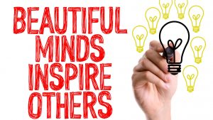 Această imagine ilustrează un citat inspirațional care subliniază puterea minților creatoare de a inspira și motiva. O mână desenează manual și pune în evidență acest mesaj profund, oferind o perspectivă vizuală asupra impactului pozitiv al gândirii inovatoare și al biografiilor de succes.