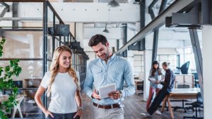 Colegi de Afaceri Utilizând o Tabletă Digitală în Spațiul de Lucru: Imaginea prezintă colegi de afaceri tineri și zâmbitori, folosind o tabletă digitală într-un mediu de lucru modern. Această imagine reflectă importanța tehnologiei digitale în lumea afacerilor de azi, subliniind rolul esențial pe care îl joacă învățarea și adaptarea la noile instrumente în succesul profesional. Un exemplu perfect al modului în care lectura cărților de business poate ajuta profesioniștii să se mențină la curent cu ultimele tendințe.