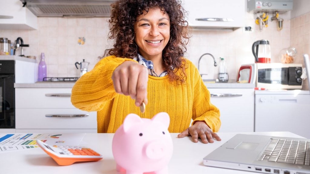 Femeie fericită de culoare economisind bani pentru viitor, un exemplu pozitiv de planificare financiară și importanța lecturii cărților de educație financiară.