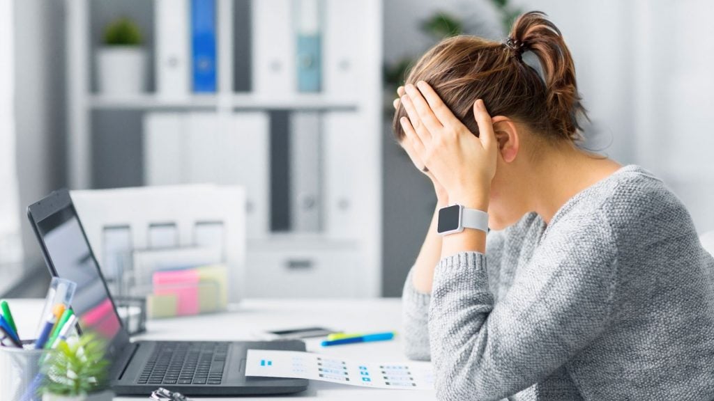 Tânără arătând semne de stres la biroul ei, evidențiind importanța gestionării stresului într-un mediu de lucru.
