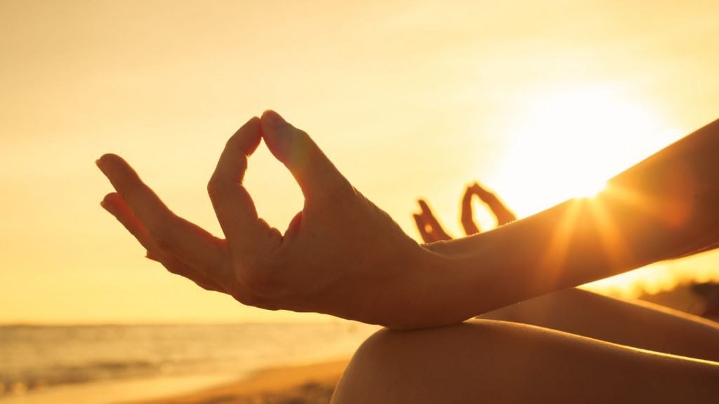 Meditație mindfulness pe plajă la apus, moment de liniște și conștientizare