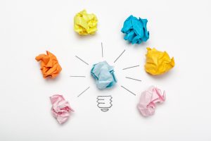 Imaginea prezintă o reprezentare vizuală abstractă a conceptelor de auto-reflecție, introspecție, conștientizare de sine și auto-observare. În centru, se află o bucată de hârtie îndoită de culoare albastră desenată cu linii radiale ce duc spre mai multe bile de hârtie mototolită de diverse culori: galben, turcoaz, portocaliu, roz, și încă un galben, așezate într-un cerc în jurul centrului. Aceasta poate simboliza procesul de gândire centralizat și diversele aspecte sau rezultate ale reflectării personale.