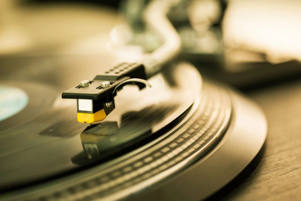 Un pickup de platan delicat atinge un disc de vinil, evidențiind detaliile fine ale înregistrării analogice și rafinamentul tehnologic al redării muzicale clasice.