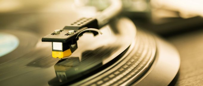 Un pickup de platan delicat atinge un disc de vinil, evidențiind detaliile fine ale înregistrării analogice și rafinamentul tehnologic al redării muzicale clasice.