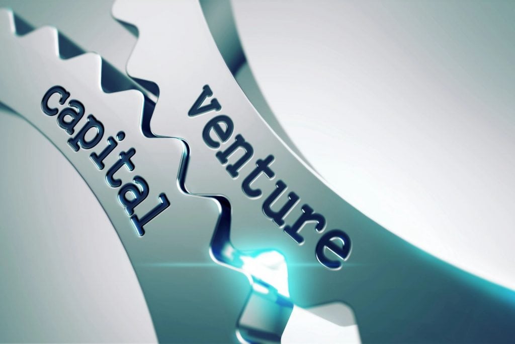 O imagine cu două roți dințate metalice, interconectate, inscripționate cu cuvintele "venture" și "capital". Acestea simbolizează colaborarea și dinamismul din lumea venture capital-ului, unde investițiile și inovația funcționează împreună pentru a crea creștere economică și dezvoltare tehnologică. Imaginea reflectă esența parteneriatului între investitori și startup-uri, elementele cheie care propulsează progresul în industriile emergente.